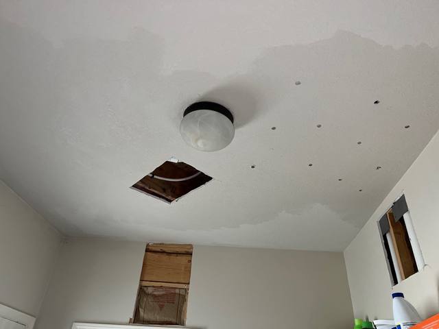 Water-stained ceiling with wet drywall cut out below a failed upstairs supply line in Lee’s Summit, MO