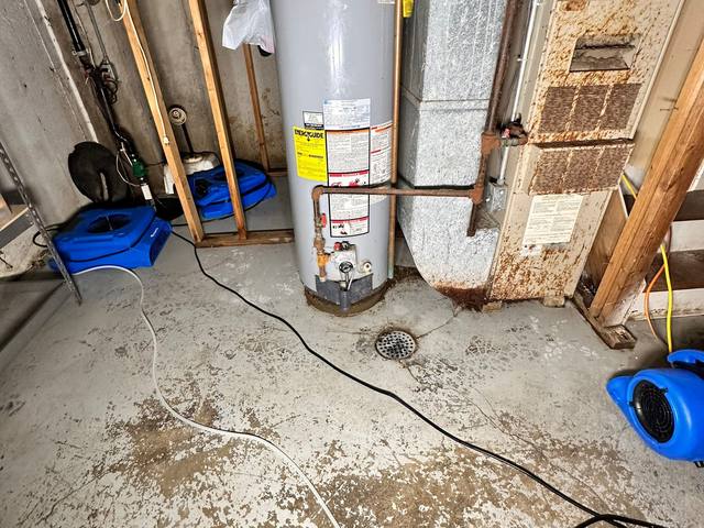 Air movers drying a wet basement floor around the water heater in Prairie Village, KS